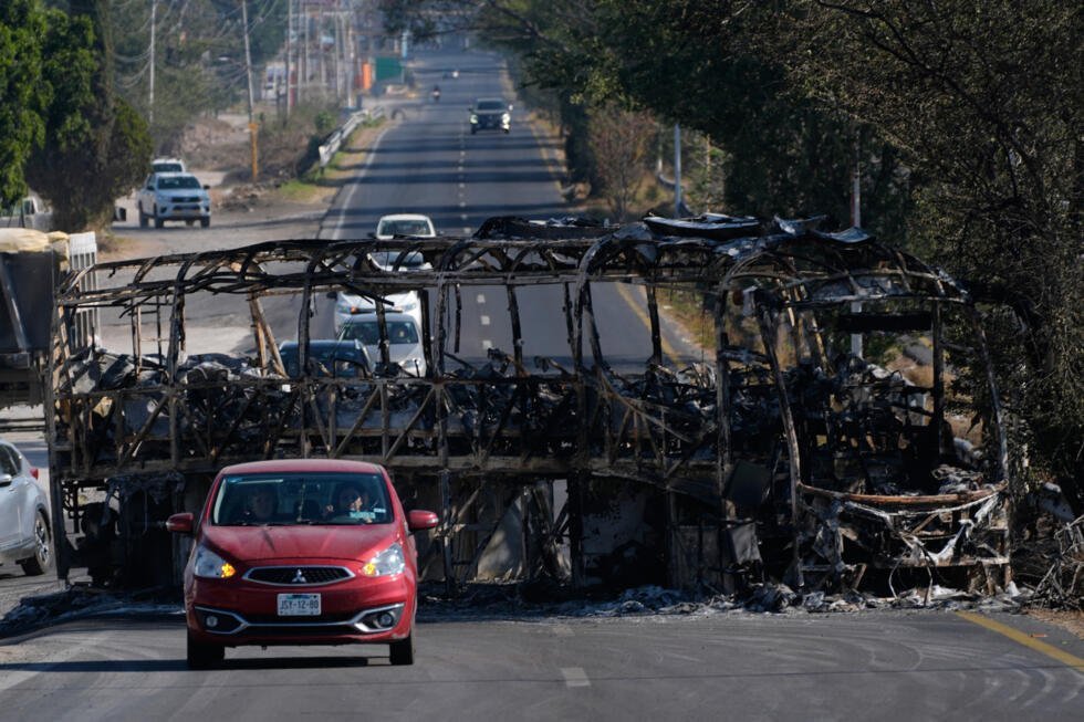 Un autobús calcinado bloquea una carretera en Guadalajara, México, luego de que elementos del cartel Jalisco Nueva Generación llevaran a cabo acciones violentas para rechazar la eliminación de su líder Rubén Nemesio Oseguera Cervantes. 23 de febrero de 2026.