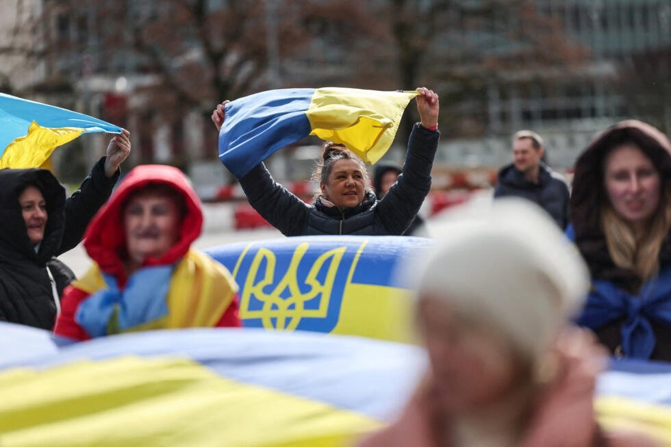 Personas portan banderas ucranianas en una protesta cerca de la oficina de las Naciones Unidas, el día de las conversaciones de paz mediadas por Estados Unidos entre Rusia y Ucrania en Ginebra, Suiza, el 17 de febrero de 2026.