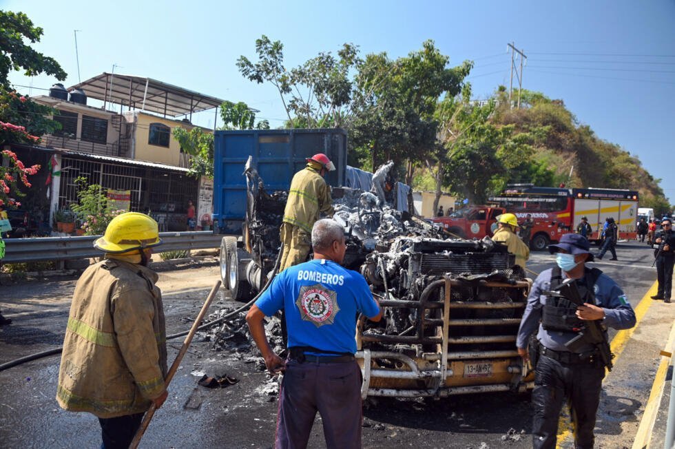 Los bomberos extinguen un camión calcinado incendiado en Acapulco, en el estado de Guerrero (México), el 22 de febrero de 2026.