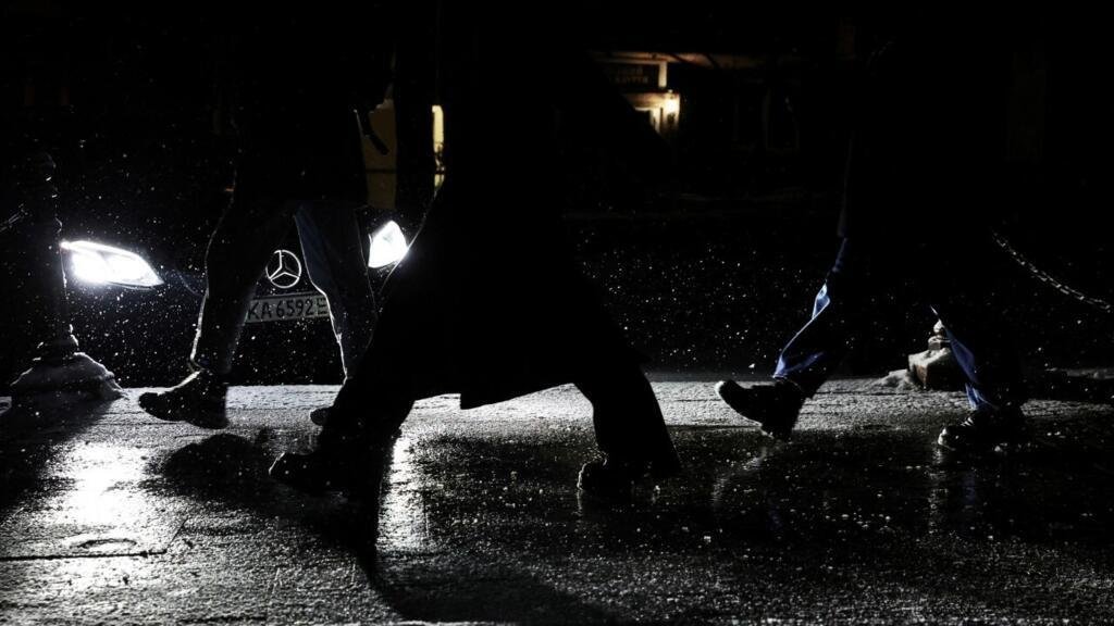 La gente camina por las calles oscurecidas durante los cortes de electricidad mientras cae la nieve en Kyiv, Ucrania, 3 de diciembre de 2022.