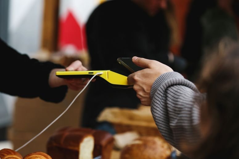 Una persona paga sin contacto, usando su celular y una terminal.