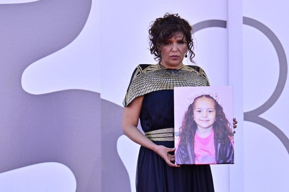 La directora tunecina Kaouther Ben Hania sostiene un retrato de la fallecida niña palestina Hind Rajab durante la alfombra roja de la película 'La voz de Hind Rajab', presentada en el 82º Festival Internacional de Cine de Venecia, el 3 de septiembre de 2025.