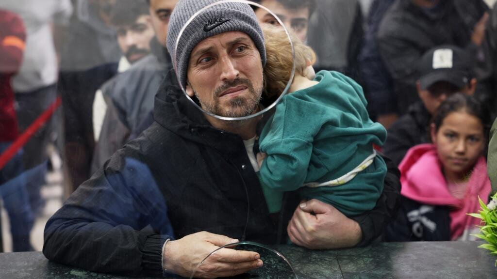 Un hombre sirio lleva a un niño en brazos mientras cruzan la frontera entre Siria y el Líbano para entrar en Siria, huyendo del Líbano a causa de los ataques aéreos israelíes, en Jdeidet Yabous, Siria, el martes 3 de marzo de 2026.