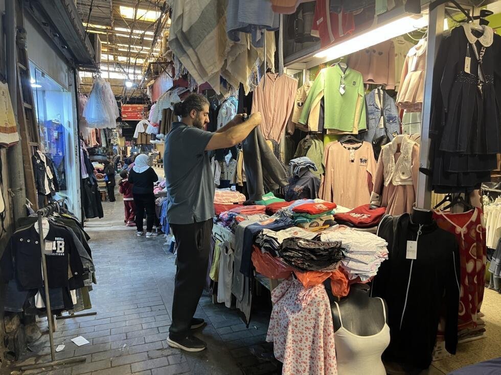 Wissam organise l'étal de sa boutique de vêtements.
