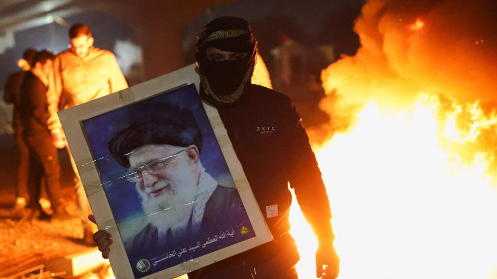 Un manifestante sostiene la imagen del líder supremo de Irán, el ayatolá Ali Jamenei, mientras los partidarios de los grupos armados chiítas de Irak intentan avanzar hacia la embajada estadounidense en Bagdad. 1 de marzo de 2026.