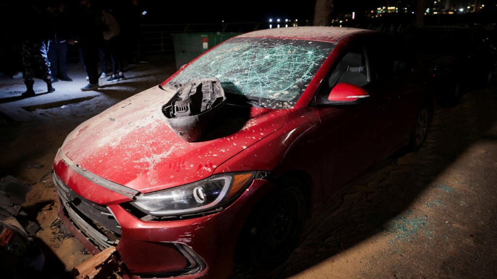 Personas se reúnen junto a un carro afectado o en el lugar donde un ataque con dron alcanzó otro vehículo en Ramlet al-Baida, en la Corniche de Beirut, tras una escalada entre Hezbolá e Israel en medio del conflicto entre Estados Unidos, Israel e Irán, en Beirut, Líbano, el 12 de marzo de 2026.