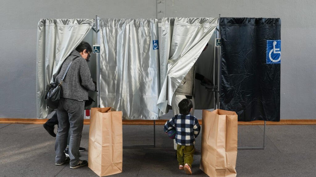 Un hombre y su hijo se presentan en una cabina de votación durante la segunda vuelta de las elecciones municipales francesas en París, el domingo 22 de marzo de 2026